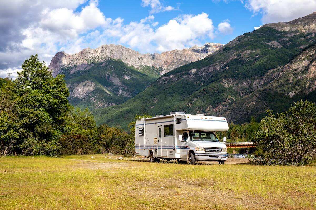 image of an rv parked backed up against a beautiful mountain range.